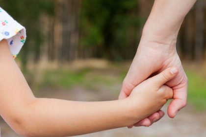 Father daughter holding hands in a meadow.