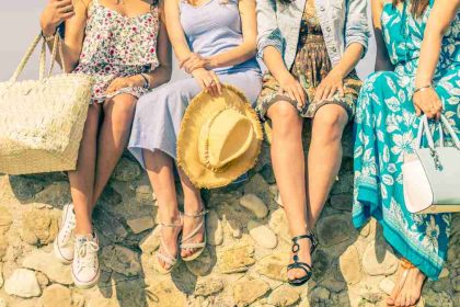 Four Women In Dresses Sitting On A Rock Wall