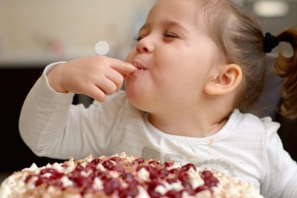 Happy Little Girl Licking Cake From Her Finger