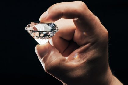 Man Holding Diamond Against Black Background