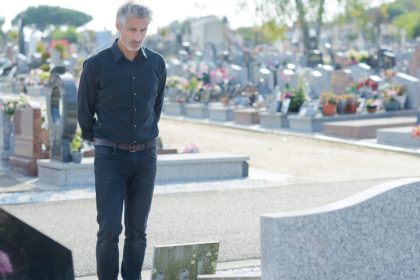 Man In Graveyard Looking At A Tombstone