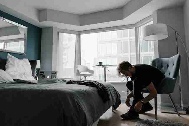 a man tying his shoes in his bedroom