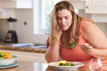 Overweight Woman Eating Healthy Food In The Kitchen