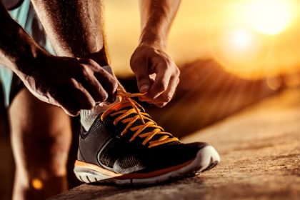 Person Tying Shoes At Sunrise With The Mountains In The Background