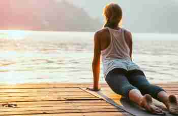 Woman Practicing Yoga By The Lake