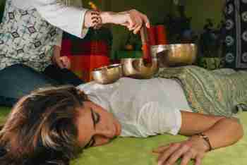 Relaxed Woman Receiving Sound Healing Treatment With Singing Bowls